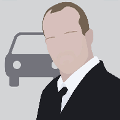 icomania:A man with short brown hair wearing a suit and in standing in front of a car